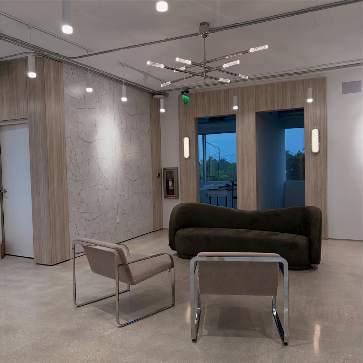 Contemporary commercial interior with lounge seating, warm wood cabinetry, and a glass meeting room