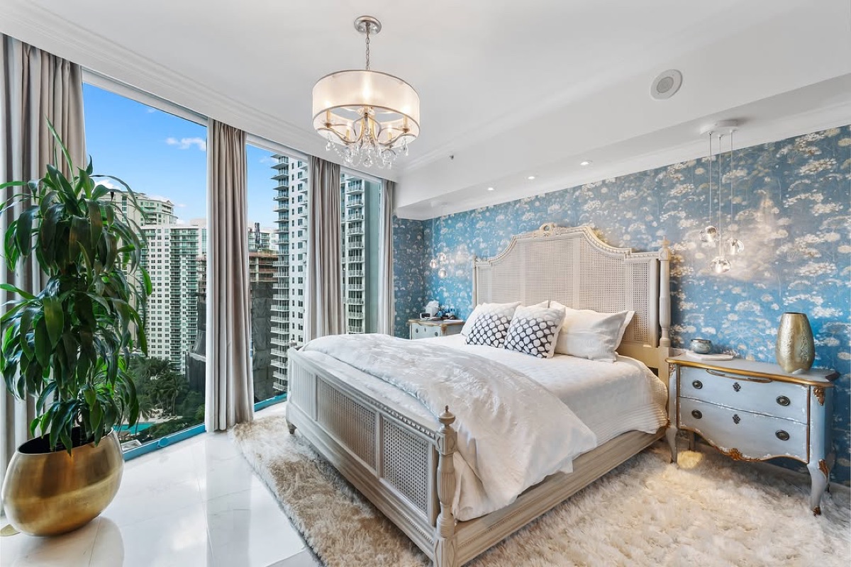 Serene high-rise bedroom with layered linens, pale blue accents, and a textured feature wall
